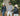 Three people wearing branded jackets in a forest setting