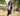 Woman in a park wearing a varsity jacket and skirt