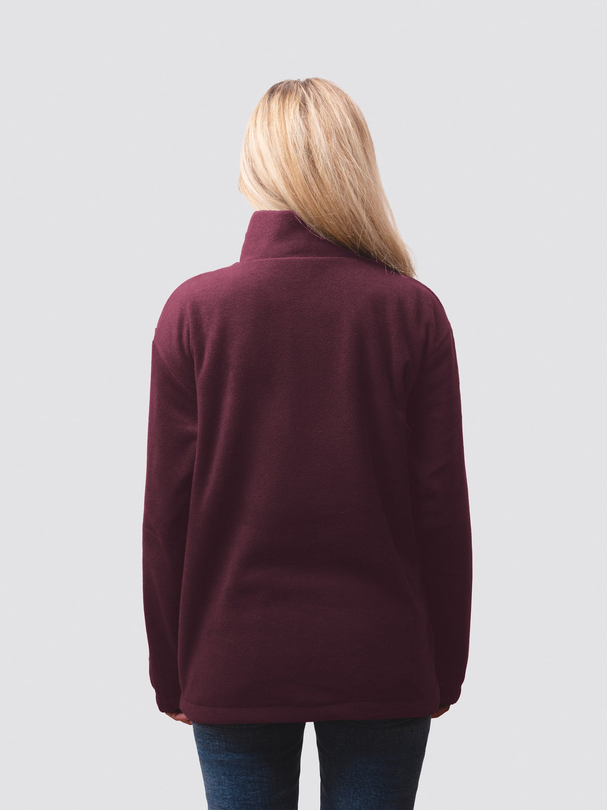 Blonde student model, wearing a burgundy 1/4 zip fleece